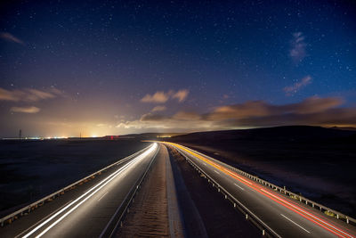 Light trails on road against sky at night