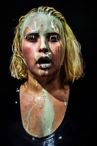Close-up portrait of young woman against black background