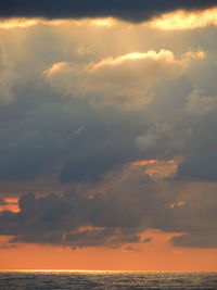 Scenic view of sea against dramatic sky during sunset