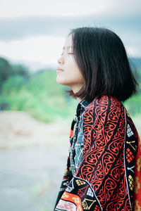 Woman looking away while standing outdoors