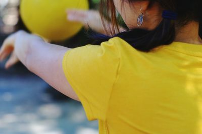 Side view of girl with arms outstretched holding ball while standing at park