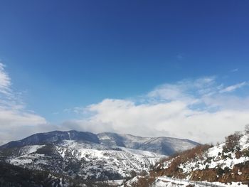 Scenic view of snowcapped mountains against blue sky