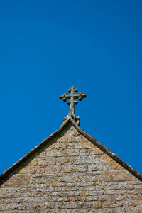 Low angle view of cross against building against clear blue sky