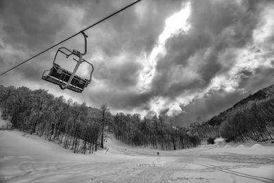 Ski lift over snowcapped mountains against sky