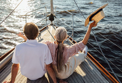 Rear view of people sitting on boat in sea