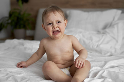 Portrait of cute baby boy lying on bed at home