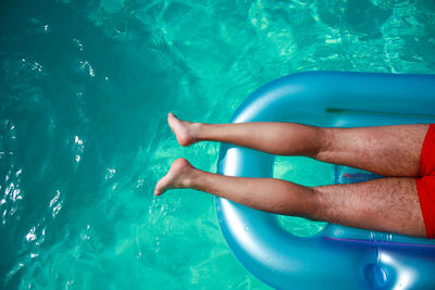 Low section of man relaxing on pool raft