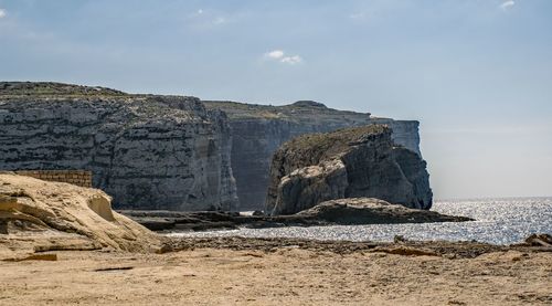 Rock formations on beach against sky