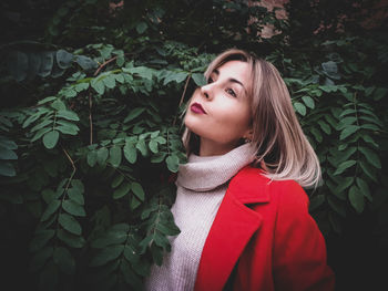 Thoughtful young woman looking away by plants