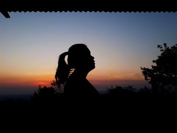 Silhouette woman standing against orange sky