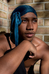 Close-up of man looking away sitting by wall