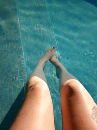 Low section of woman relaxing in swimming pool