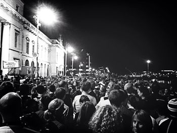 Crowd on illuminated city against sky at night