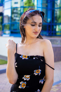 Portrait of young woman standing against building