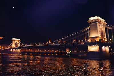 Illuminated bridge over river at night