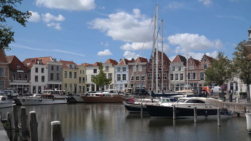 Sailboats moored on canal amidst buildings in city