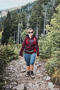 Woman with backpack hiking in mountains, spending summer vacation close to nature