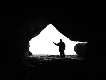 Silhouette man standing on rock in cave