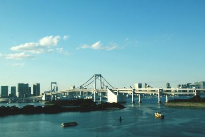 Bridge over river in city against blue sky