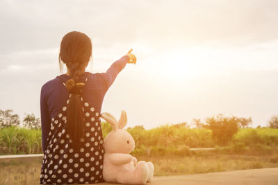 Rear view of woman with toy on field against sky