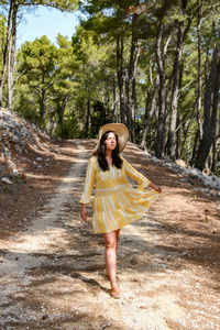 Front view of young woman in summer dress standing on path in forest. beautiful, lifestyle.