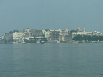 Sea by buildings against sky in city