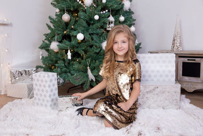 Full length of girl sitting on christmas tree