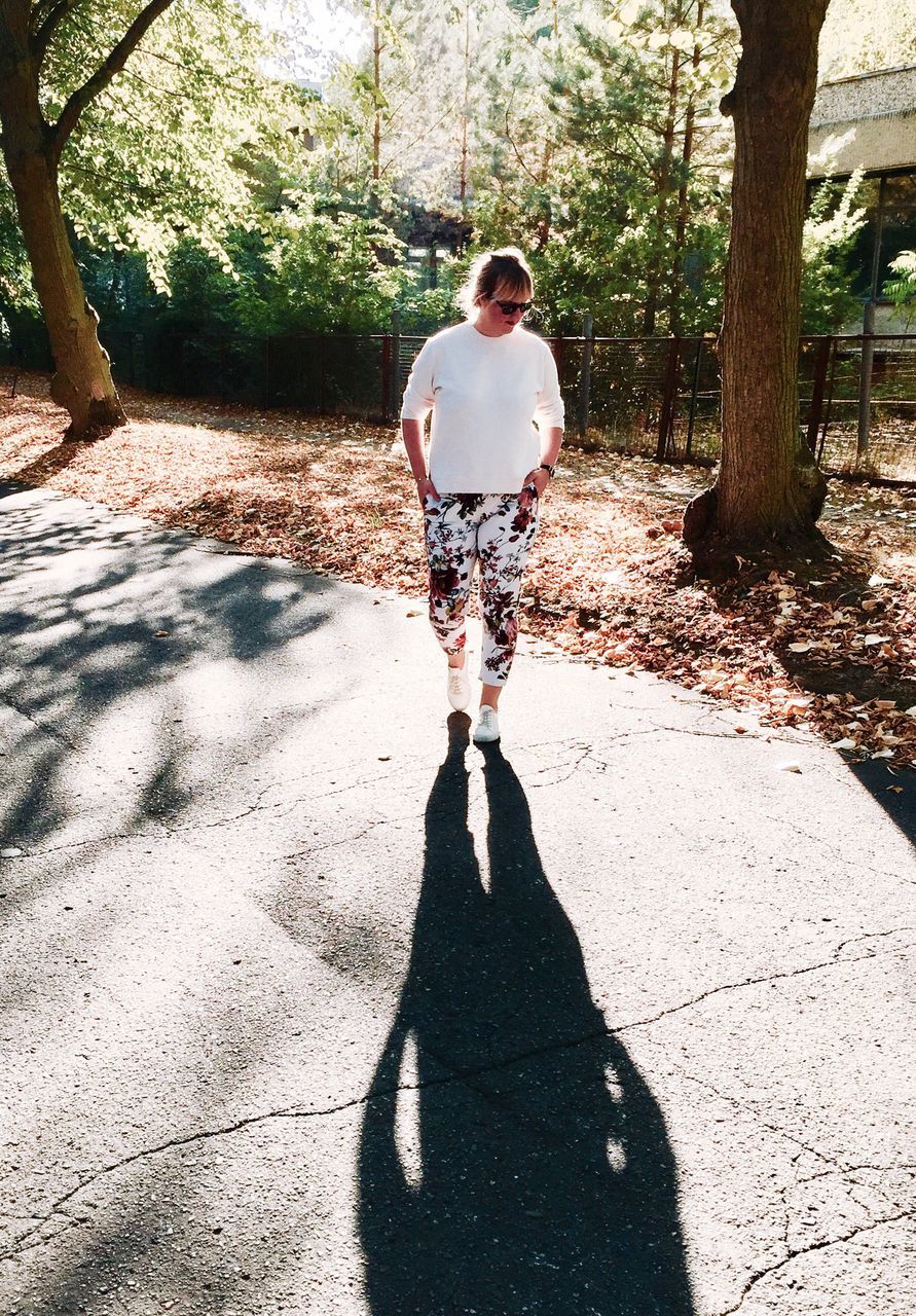 REAR VIEW OF WOMAN WITH UMBRELLA WALKING ON TREE