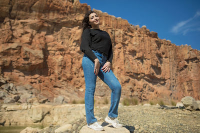 Full length of young woman standing on rock