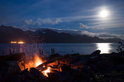 Bonfire by sea against sky at night