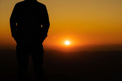 Silhouette man standing against orange sky during sunset