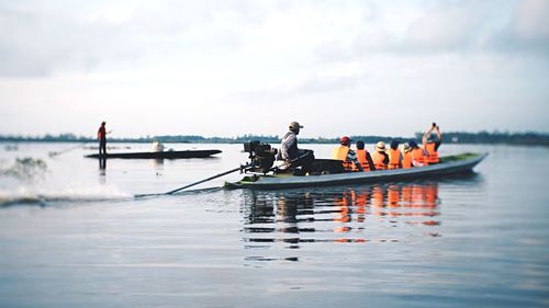 People on boat in sea against sky