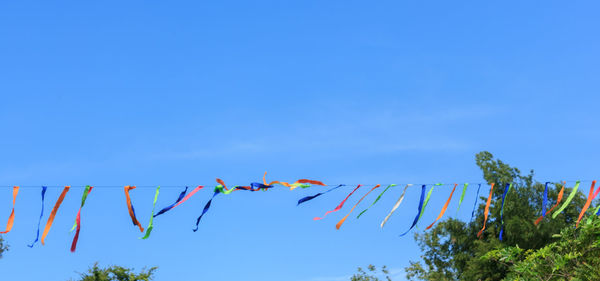 Low angle view of flags hanging against blue sky