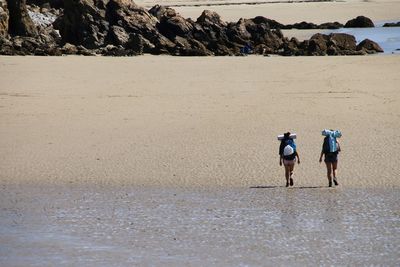 Rear view of people walking on beach