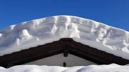 Low angle view of snow covered mountain against clear blue sky