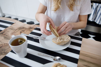 Midsection of woman holding coffee cup on table