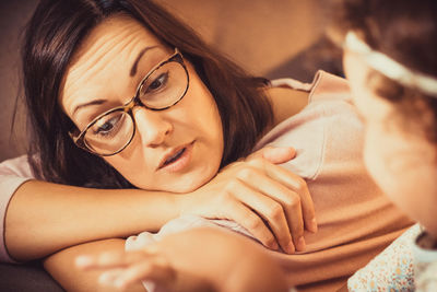 Mid adult mother communicating with her daughter while relaxing at home.