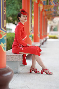 Midsection of woman in red traditional clothing sitting outdoors