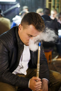 Young man smoking hookah at night