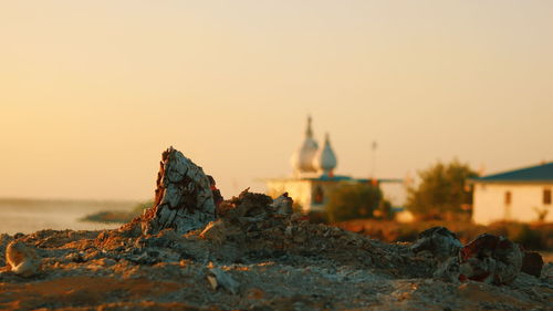 Rocks by building against clear sky during sunset