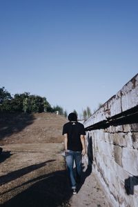 Rear view of man walking against clear sky