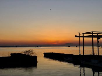 Silhouette pier over sea against sky during sunset