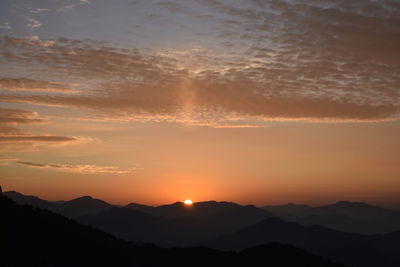 Scenic view of silhouette mountains against romantic sky at sunset