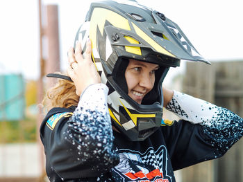 Young woman with curly hair smiling in helmet and protective gear for motocross