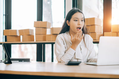 Young woman using mobile phone while sitting on table