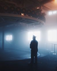 Rear view of silhouette man standing in illuminated building