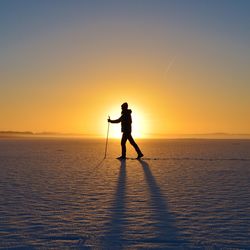 Silhouette man on snow against sky during sunset