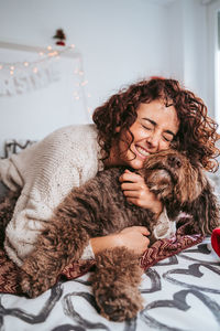 Woman hugh her dog on the bed at christmas 