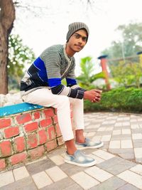 Portrait of smiling young woman standing on footpath