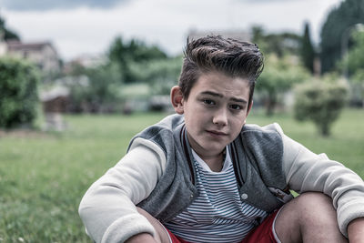 Portrait of teenage boy sitting on grassy field